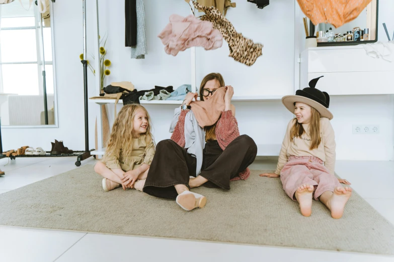 a group of women sitting on top of a rug, by Emma Andijewska, pexels contest winner, girl's room, designer clothes, happy family, brown clothes