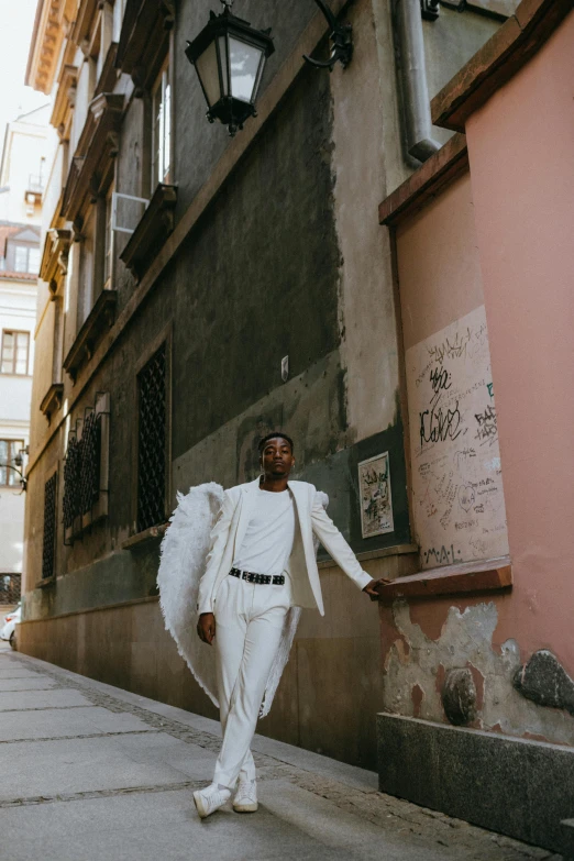 a man in a white suit walking down a street, by Matija Jama, pexels contest winner, girl with angel wings, model posing, black man, budapest