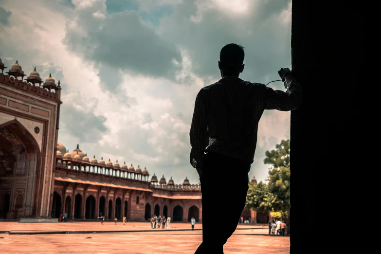 a man standing in front of a building, inspired by Steve McCurry, pexels contest winner, arabesque, shaved temple, siluettes, afternoon hangout, india