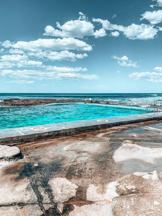 an empty swimming pool next to the ocean, pexels contest winner, rock pools, 4 k cinematic panoramic view, sydney, ocher and turquoise colors