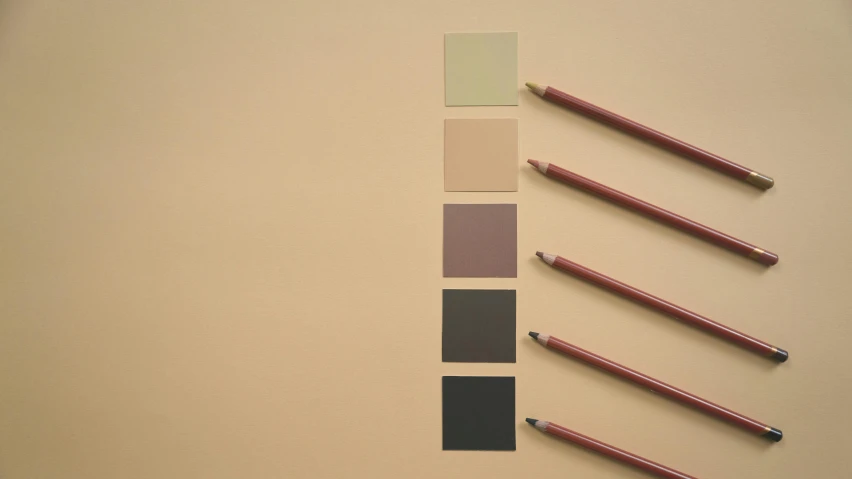 a group of pencils sitting on top of a table, a minimalist painting, inspired by Giorgio Morandi, trending on pexels, color field, taupe, black and auburn colour pallet, square shapes, matte photo