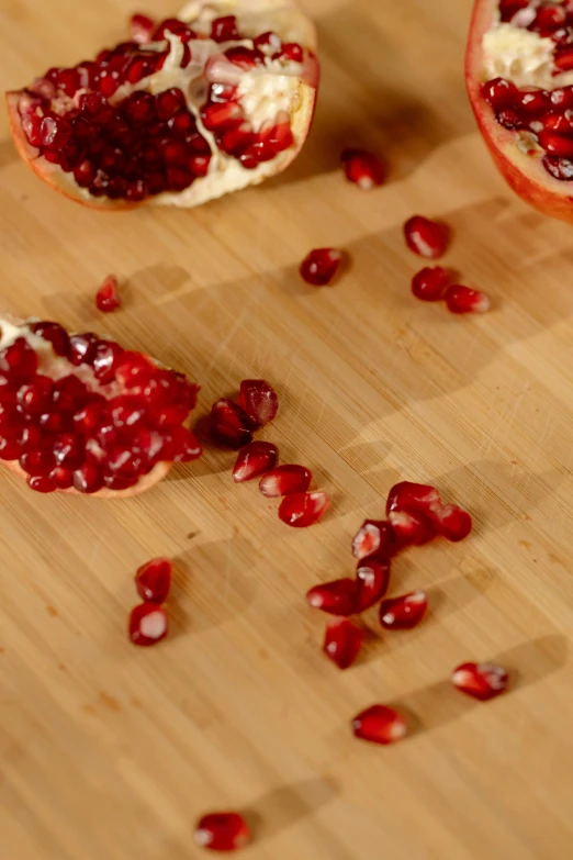 a wooden cutting board topped with pomegranates, broken, transforming, close ups, adi meyers