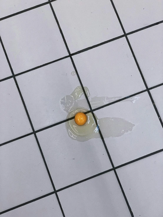 a broken egg sitting on top of a tiled floor, by Ryan Pancoast, reddit, floating bubbles, orange yellow, 🐿🍸🍋, cracked plastic wrap