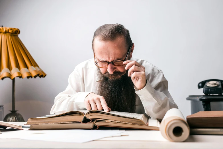 a man with a long beard reading a book, an album cover, inspired by Leo Leuppi, unsplash, old scientific documents, people at work, orthodox, nerdy music teacher with phd