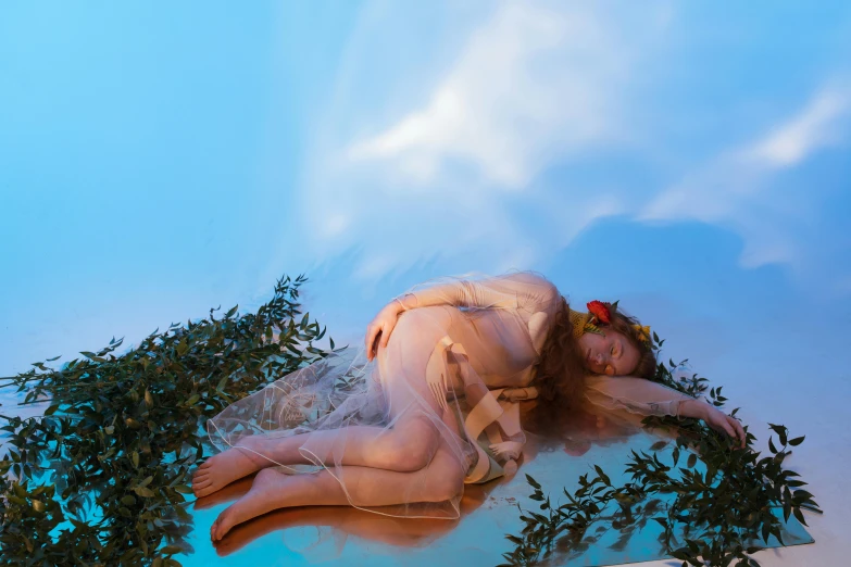 a woman laying on top of a bed next to a tree, an album cover, inspired by Konstantin Somov, unsplash, renaissance, blue sky, patricia piccinini, maternity feeling, nymph in the water