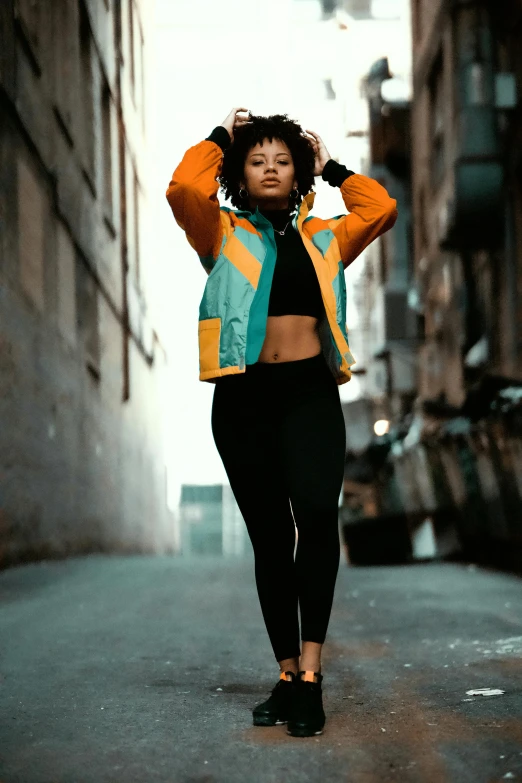 a woman standing in the middle of a city street, pexels contest winner, graffiti, wearing fitness gear, ocher and turquoise colors, black young woman, puffer jacket