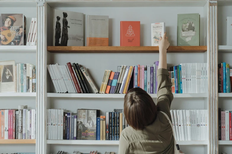 a woman reaching for a book on a bookshelf, pexels contest winner, pointing, slightly minimal, gif, profile image