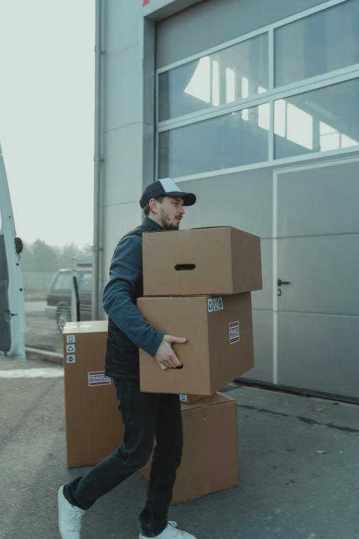 a man carrying two boxes in front of a building, grey, profile pic, leaving a room, high-quality photo