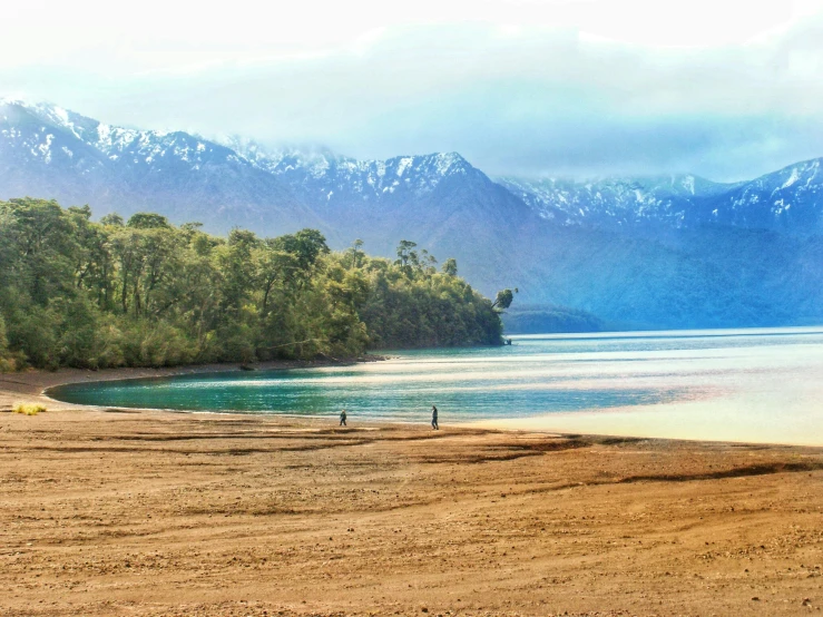 a couple of people standing on top of a sandy beach, a photo, by Sophie Pemberton, hurufiyya, lakeside mountains, 4 k photoshopped image, kahikatea, where a large