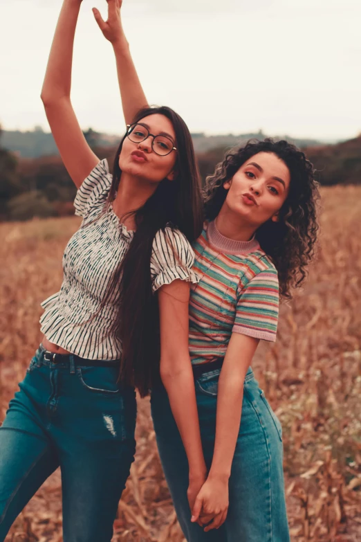 two women standing next to each other in a field, trending on pexels, wavy hair spread out, teenager, retro style ”, latinas