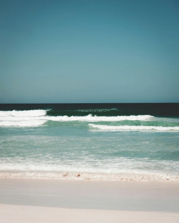 a man riding a surfboard on top of a sandy beach, pexels contest winner, minimalism, the emerald coast, photo of the middle of the ocean, south african coast, low quality photo