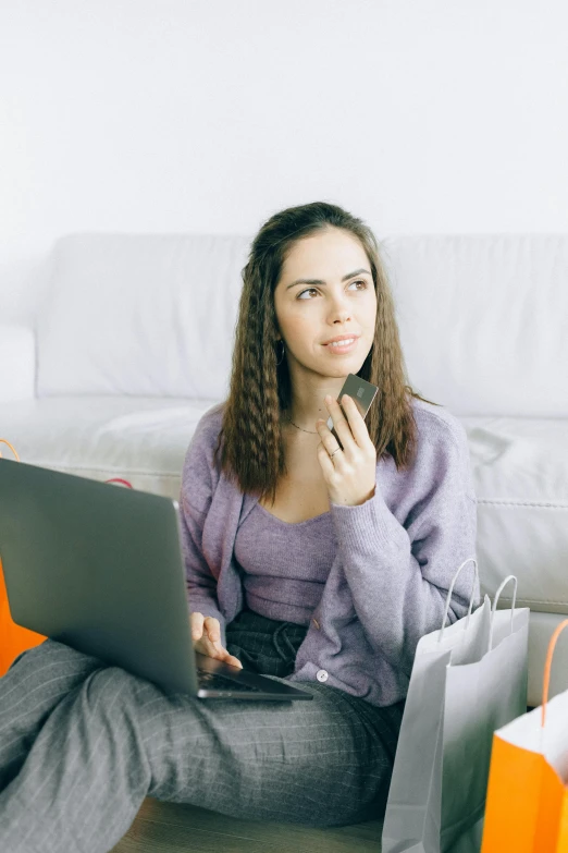 a woman sitting on the floor with shopping bags and a laptop, trending on pexels, happening, looking serious, avatar image, sitting on couch, ( ( theatrical ) )