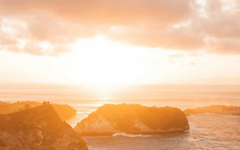 a person standing on top of a cliff next to the ocean, by Andrew Geddes, pexels contest winner, pastel orange sunset, sunlights, slide show, overcast