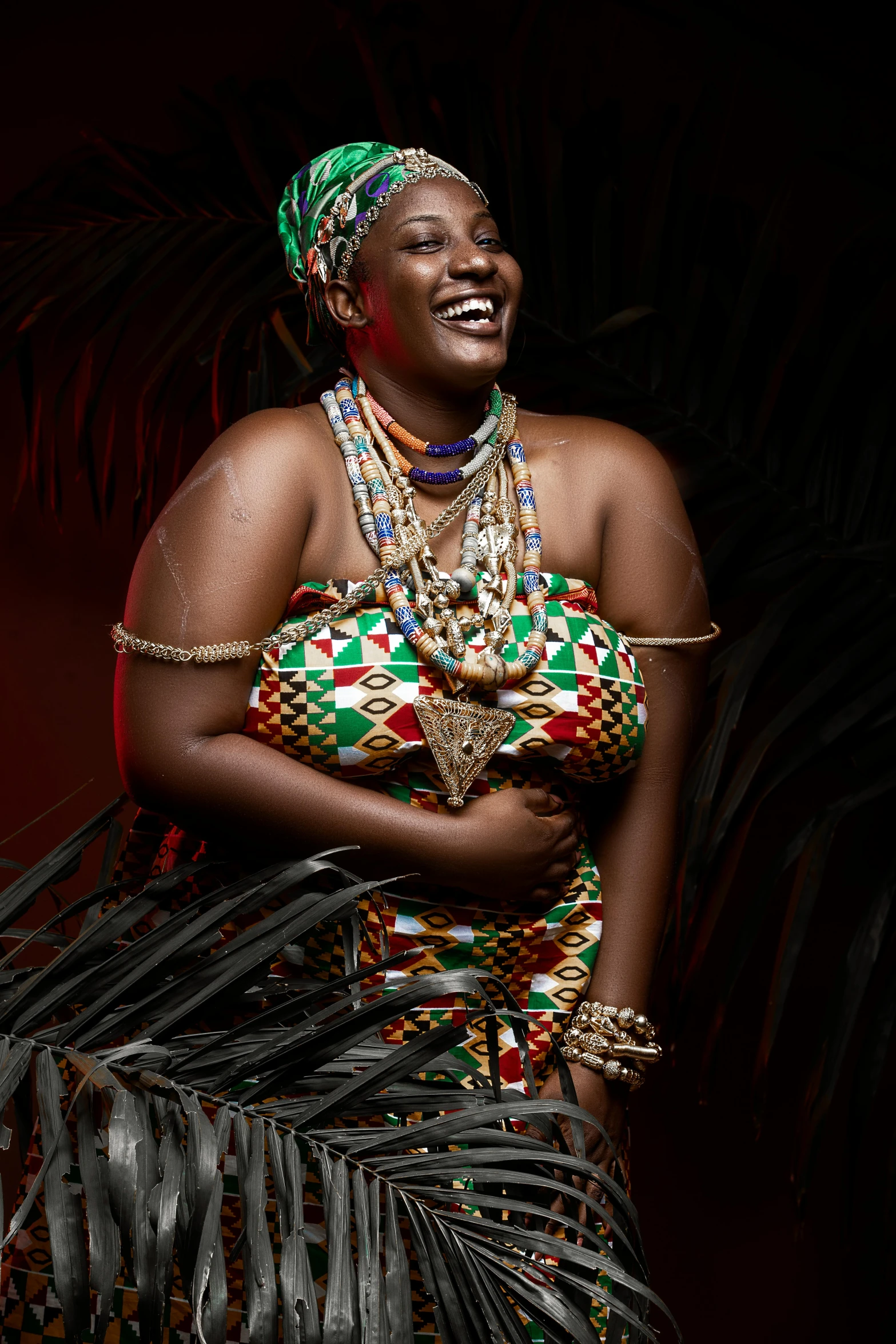 a woman in a colorful dress standing in front of a palm tree, pexels contest winner, afrofuturism, beads cross onbare chest, plus size, studio photo, traditional dress