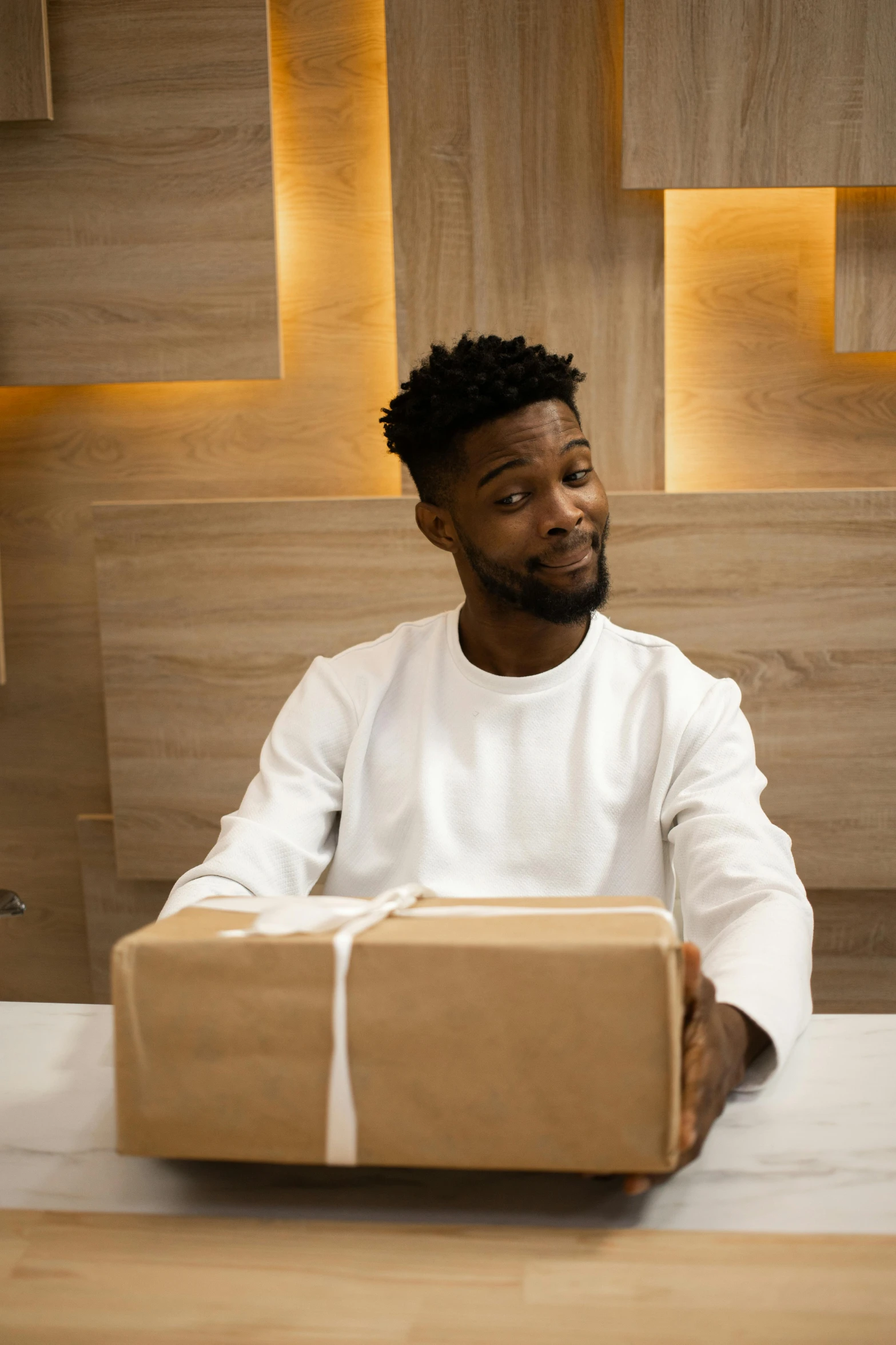 a man sitting at a table holding a box, pexels contest winner, jaylen brown, giving gifts to people, ( ( theatrical ) ), 2 1 savage