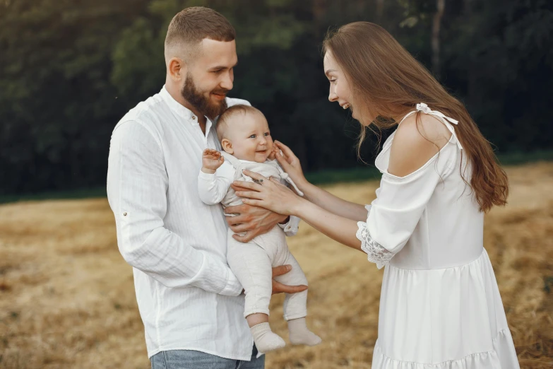 a man and woman holding a baby in a field, pexels contest winner, attractive man, white, 15081959 21121991 01012000 4k, cute and lovely