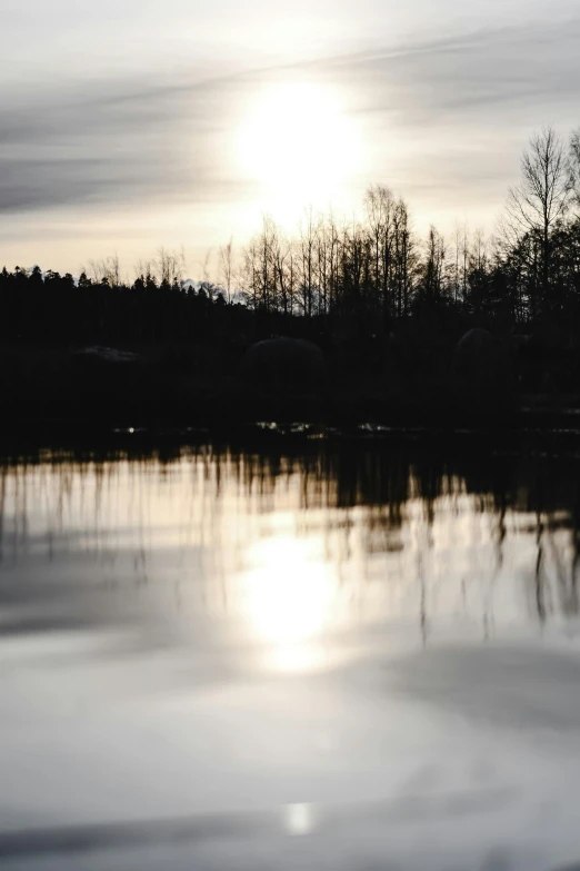 a body of water with trees in the background, a picture, inspired by Eero Järnefelt, unsplash, tonalism, evening sun, water reflection!!!!!, spring evening, grey