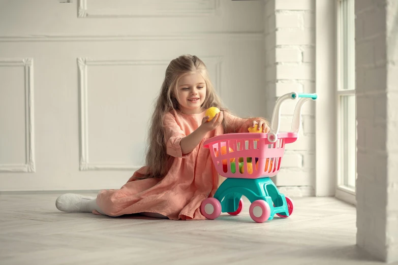 a little girl sitting on the floor with a toy shopping cart, pink and teal, fruit, wētā fx, multiple stories