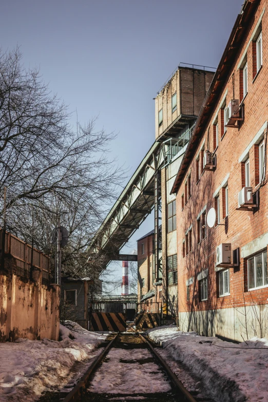 a train traveling down train tracks next to a tall building, inspired by Elsa Bleda, unsplash, graffiti, entrance to abandoned mine, ground level view of soviet town, in sunny weather, industrial machinery