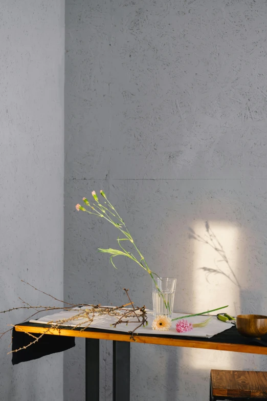 a wooden table topped with a vase filled with flowers, inspired by Martinus Rørbye, unsplash, minimalism, lighting on concrete, pressed flowers, ray tracing lighting, sparse detail