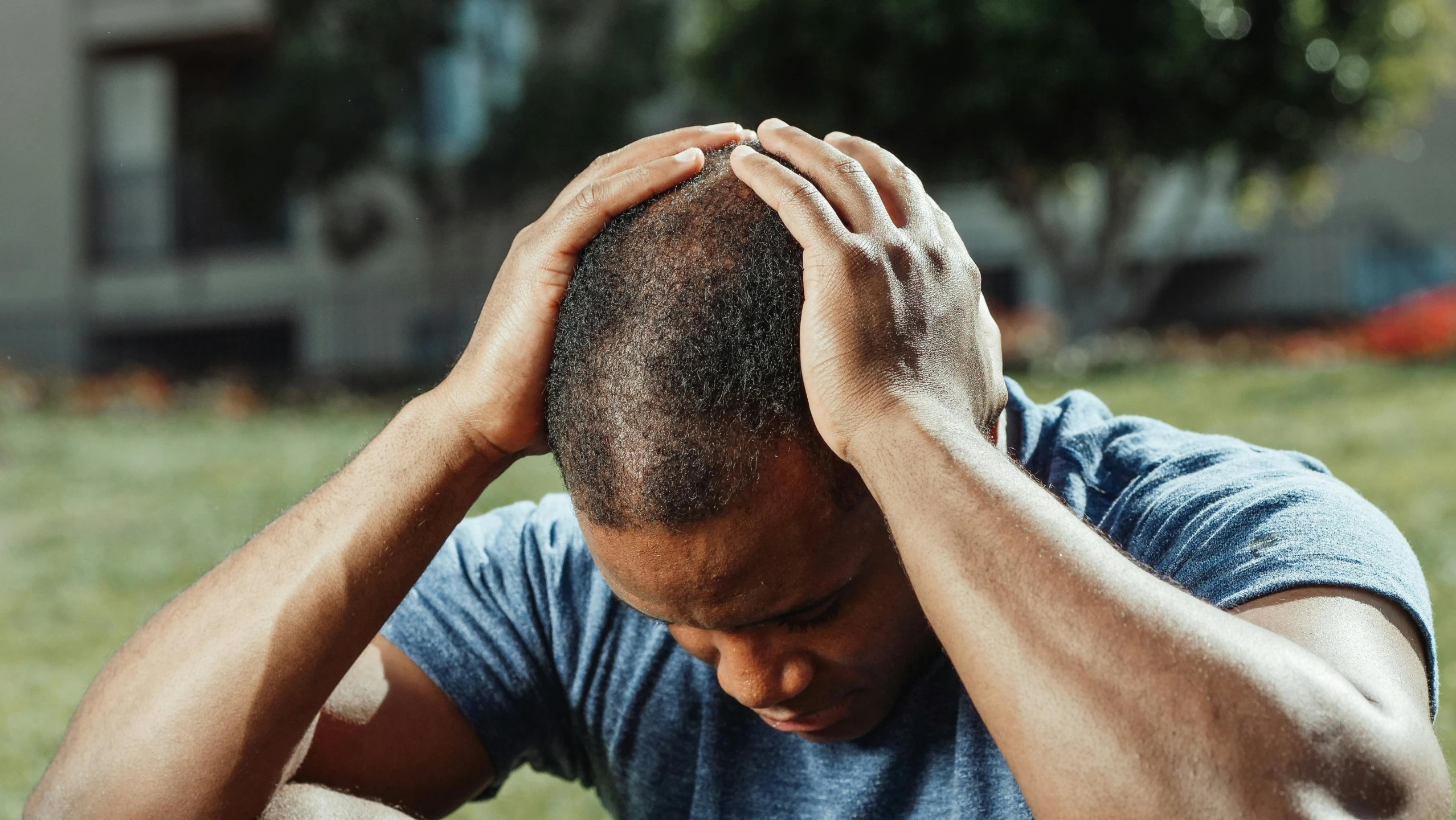 a man sitting in the grass with his head in his hands, trending on pexels, renaissance, swollen muscles, balding, sydney park, crown on head