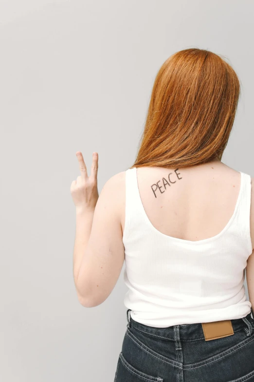 a woman with a peace sign tattooed on her back, trending on pexels, renaissance, sadie sink, plain background, journalism photo, hidden message