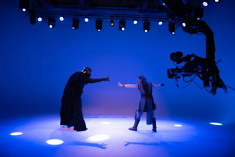 a couple of people standing on top of a stage, interactive art, gandalf fighting darth vader, production photo, indigo, sufism