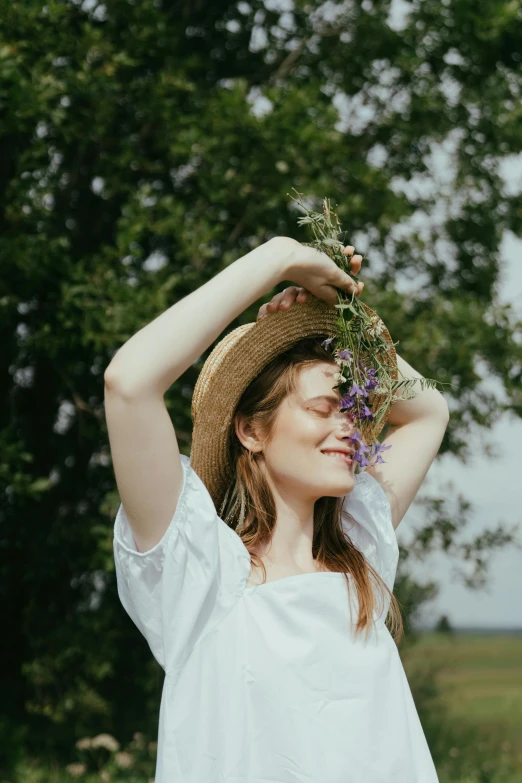 a woman standing in a field holding a bunch of flowers, pexels contest winner, renaissance, branches sprouting from her head, wearing a cute hat, dressed in a white t shirt, playful pose