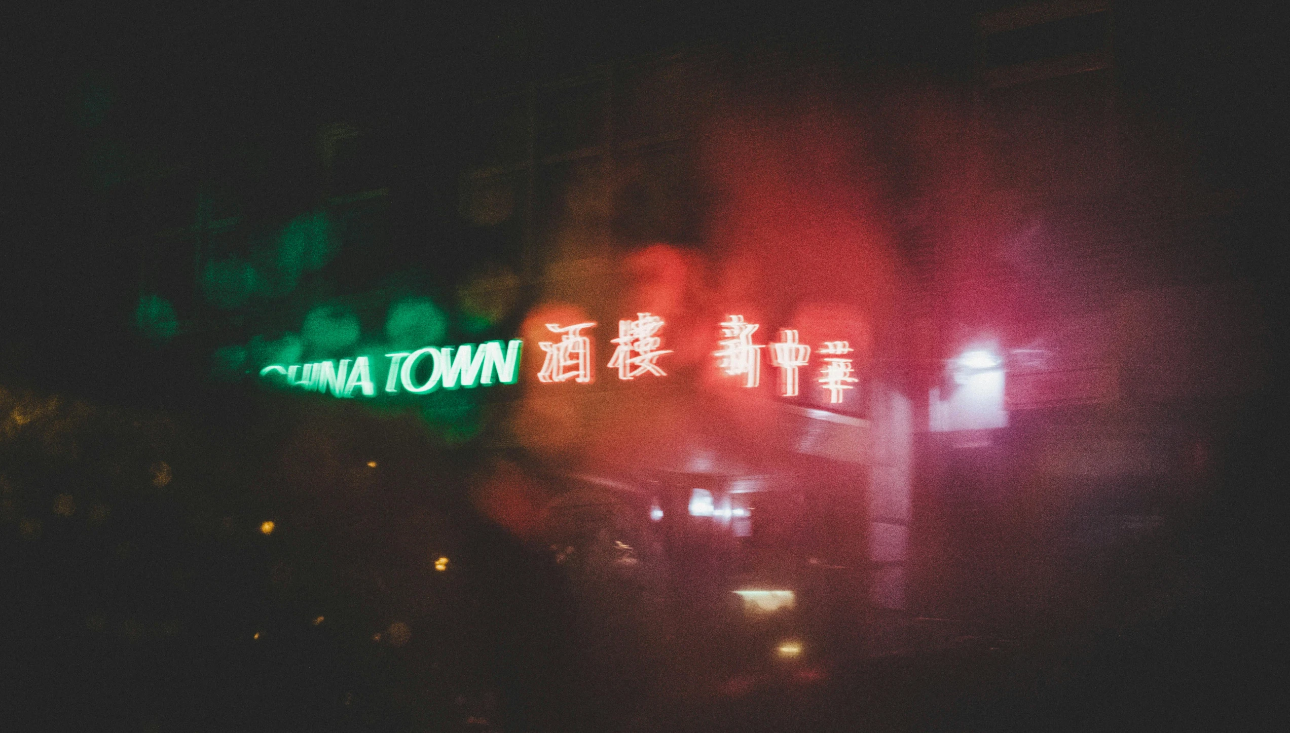 a green street sign sitting on the side of a road, by Emma Andijewska, pexels contest winner, graffiti, chinatown bar, foggy neon night, junk town, background image