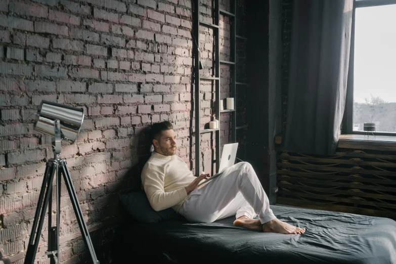 a man sitting on a bed reading a book, trending on pexels, sitting at a computer, leaning against the wall, vitaly bulgarov, cory loftis