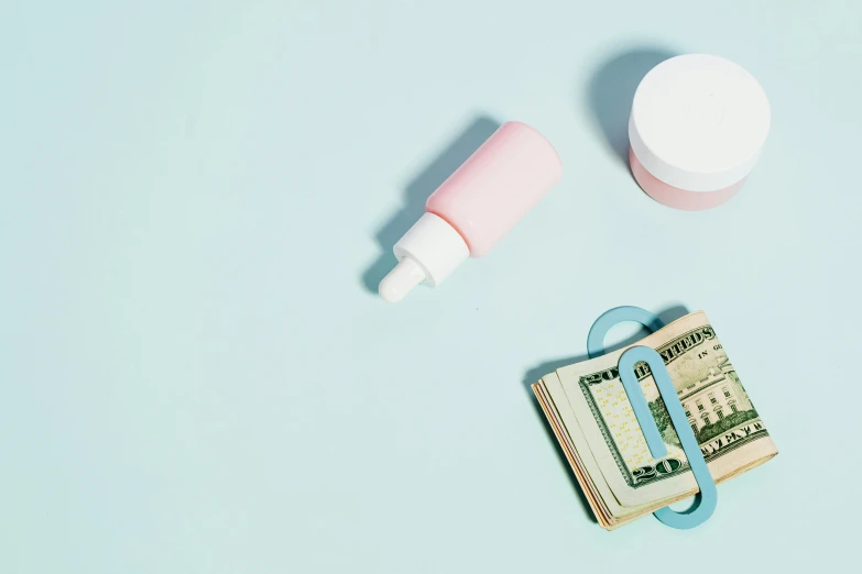 a pair of scissors sitting on top of a stack of money, a still life, trending on unsplash, minimalism, small vials and pouches on belt, skincare, blue and pink color scheme, thumbnail