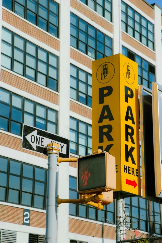 a number of street signs on a pole in front of a building, a photo, by Robert Peak, trending on pexels, yellow awning, a park, berenice abbott & john j. park, set inside of parking garage