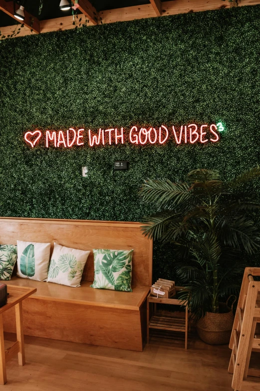 a green wall with a neon sign that says made with good vibes, trending on pexels, cozy cafe background, sustainable materials, sitting on a couch, profile image