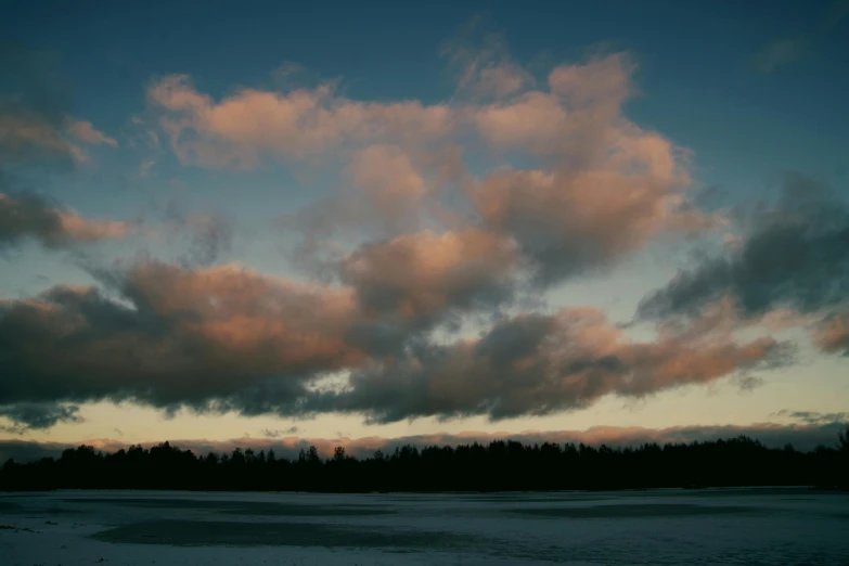 a large body of water under a cloudy sky, an album cover, by Jaakko Mattila, unsplash, romanticism, outside winter landscape, light pink clouds, late afternoon, sky forest background