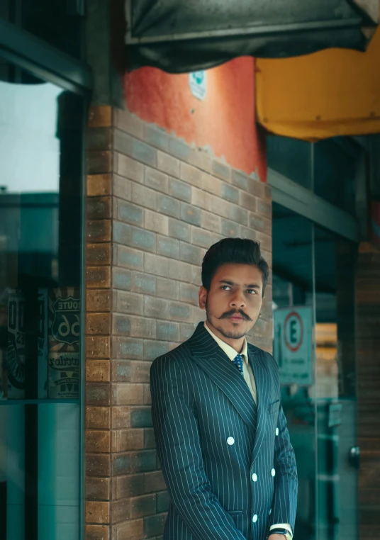 a man in a suit leaning against a brick wall, an album cover, by Elsa Bleda, unsplash, mexican mustache, standing in a restaurant, androgynous person, dressed like in the 1940s