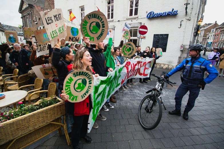 a group of people holding signs on a city street, plasticien, green fire, delft, 🚿🗝📝