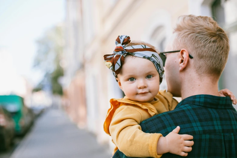 a man holding a baby in his arms, pexels contest winner, wearing a headband, square, owen klatte, very stylish