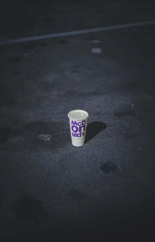 a cup that is sitting on the ground, by Holger Roed, purple rain, low quality photo, billboard image, low iso