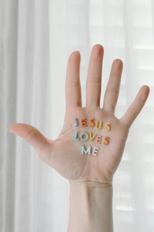 a person's hand with the word jesus loves me written on it, by Robbie Trevino, pexels, made of candy, young almighty god, lgbt, open palm