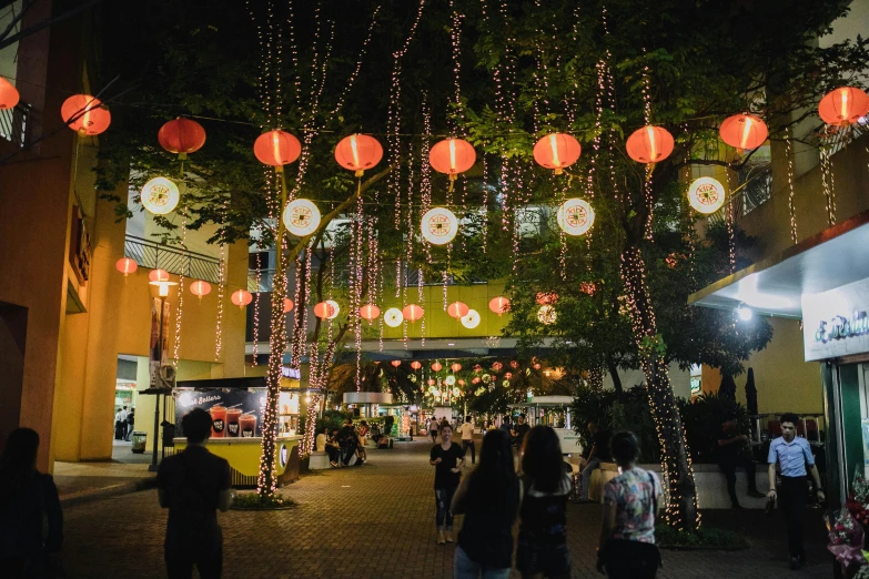 a group of people walking down a street at night, lush plants and lanterns, set on singaporean aesthetic, square, festive