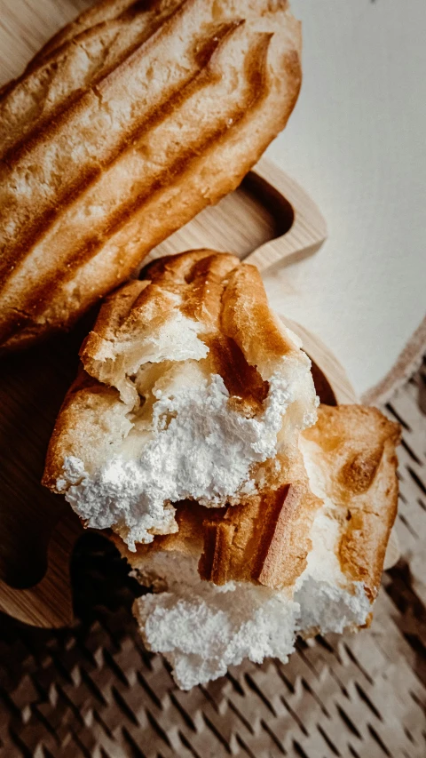 a couple of doughnuts sitting on top of a wooden table, detailed product image, whipped cream, holding a baguette, high quality photo