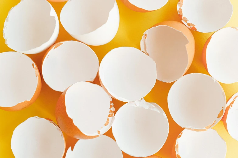 a bunch of white eggs sitting on top of a yellow surface, by Ellen Gallagher, trending on pexels, plasticien, torn paper edges, cups and balls, white and orange, round-cropped