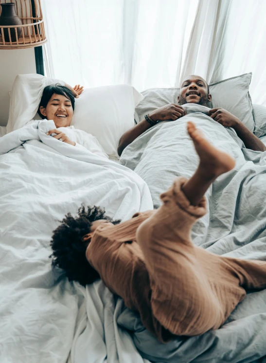 a man and woman laying in bed next to each other, pexels contest winner, happening, portrait of family of three, having a great time, thumbnail, kids playing