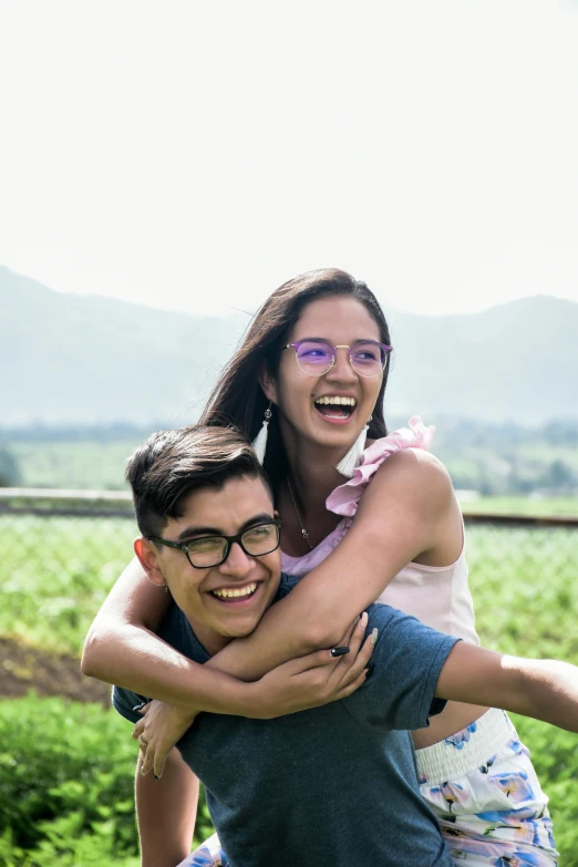 a man riding on the back of a woman, pexels contest winner, wearing medium - sized glasses, hills in the background, teen, both laughing