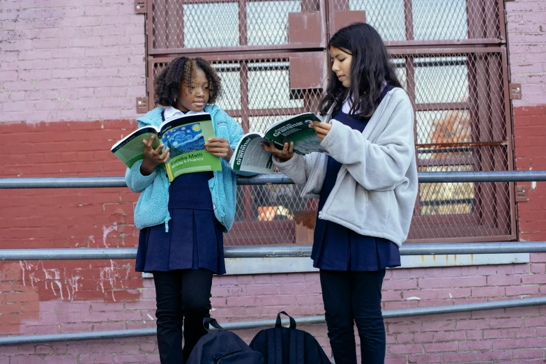 a couple of young girls standing next to each other, pexels contest winner, ashcan school, holding books, schomburg, environmental shot, scene from live action movie