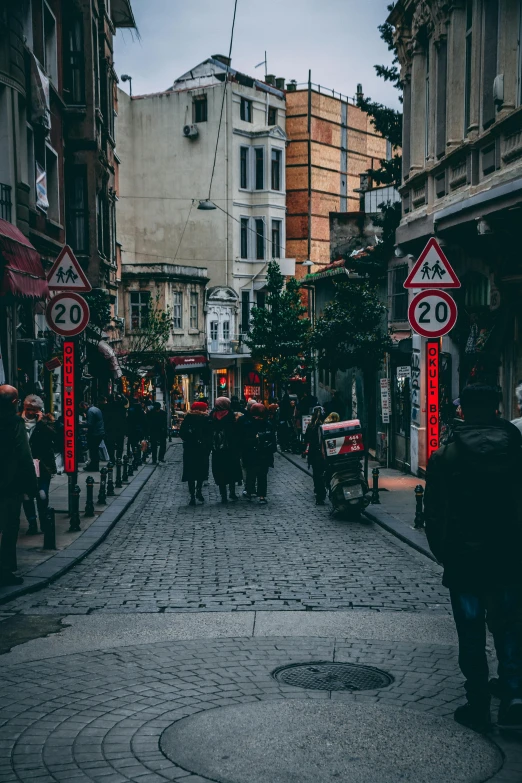 a group of people walking down a street next to tall buildings, istanbul, street signs, stores, top selection on unsplash