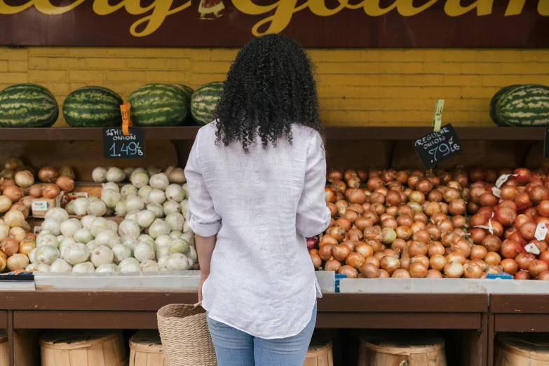 a woman standing in front of a produce stand, by Carey Morris, pexels contest winner, wearing a linen shirt, curls on top, back - shot, 15081959 21121991 01012000 4k