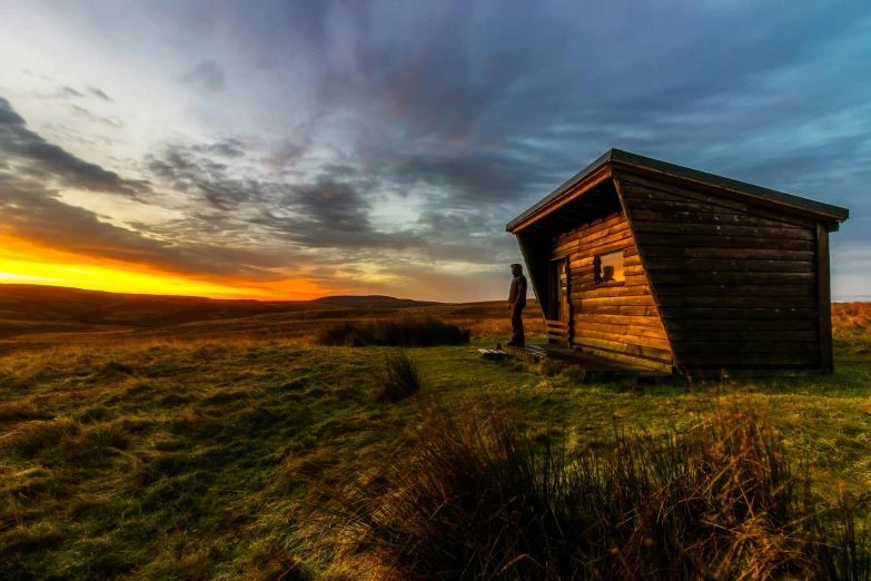 a small cabin sitting on top of a grass covered field, by Jessie Algie, pexels contest winner, renaissance, looking off into the sunset, marsden, ultrawide landscape, brown