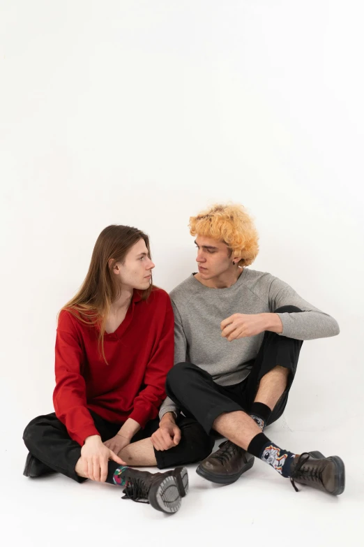 a man and a woman sitting next to each other, trending on unsplash, antipodeans, red sweater and gray pants, nonbinary model, on white background, thoughtful )