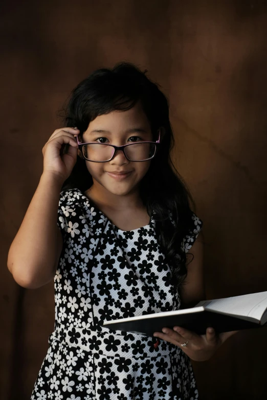 a little girl with glasses reading a book, a portrait, pexels contest winner, portrait of modern darna, studious, malaysian, black